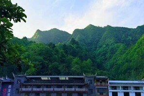 A traditional building with multiple levels and balconies, surrounded by lush green mountains. - Shengshi Fengqing Boutique Inn (Zhangjiajie)