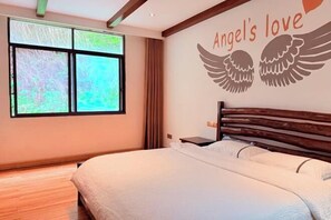 A bedroom with a bed, a window with a view, and a wall with 'Angel's love' and wings. - Shengshi Fengqing Boutique Inn (Zhangjiajie)