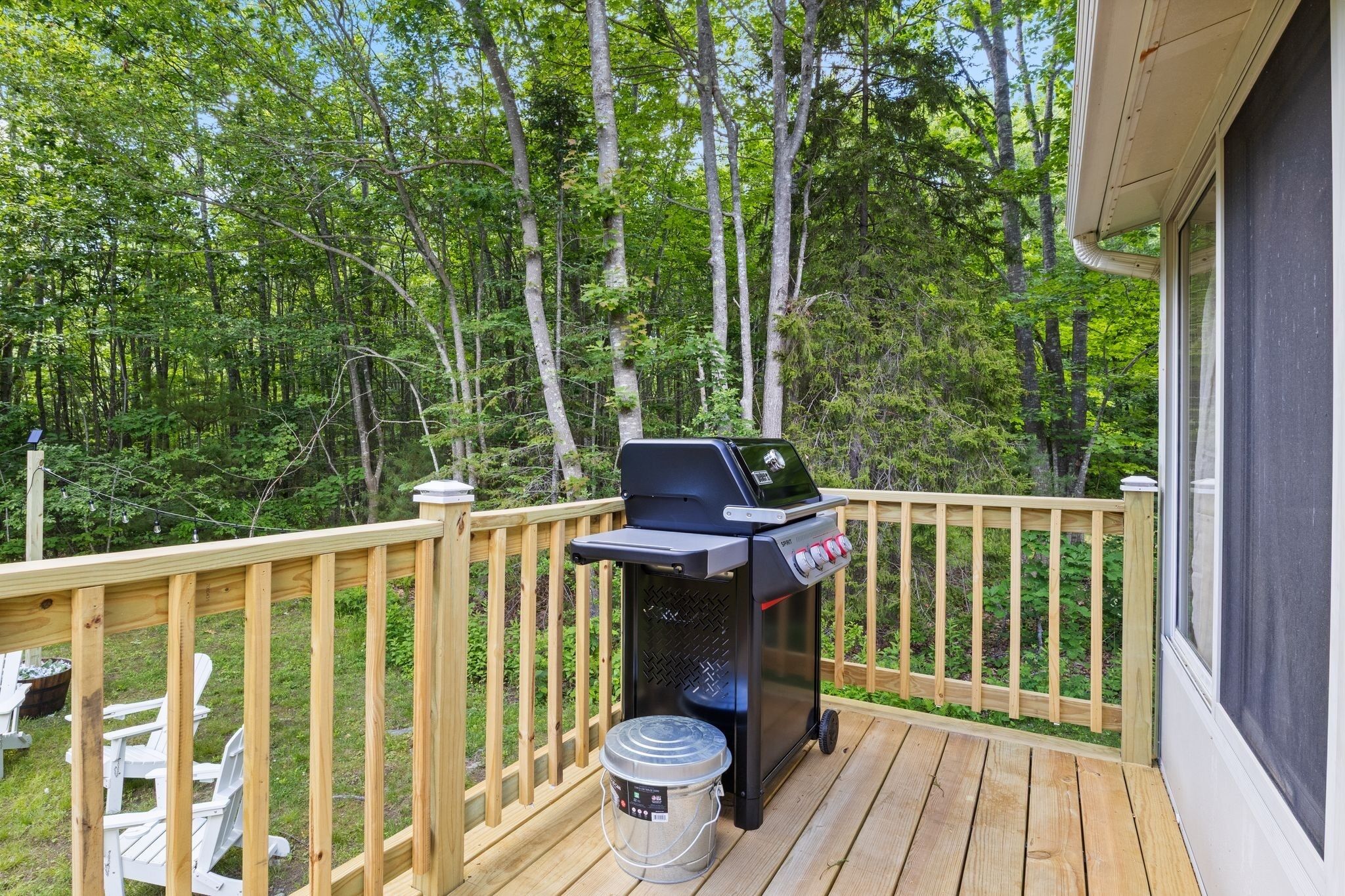 Una terraza con una parrilla, un cubo y una silla.