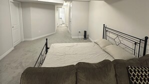 A bedroom with a bed, a couch, and a hallway leading to another room.