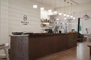A modern kitchen with a wooden island, hanging pendant lights, and a visible logo on the wall.