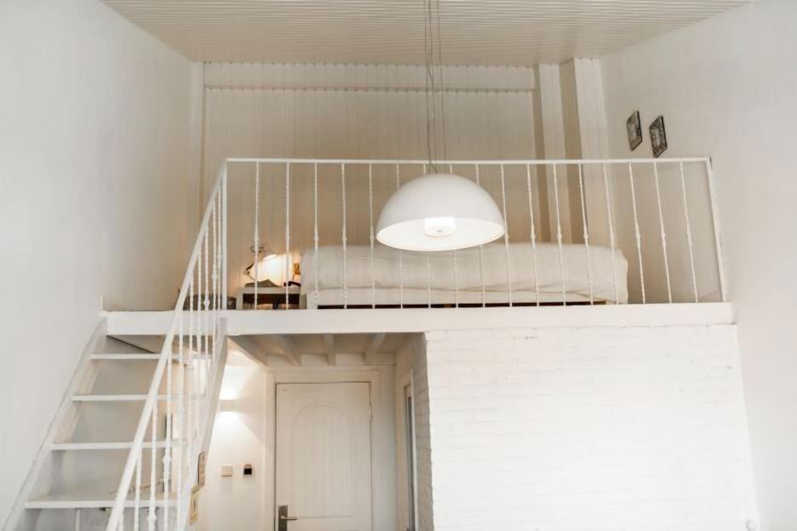 A white interior with a bunk bed, a staircase, and a door.