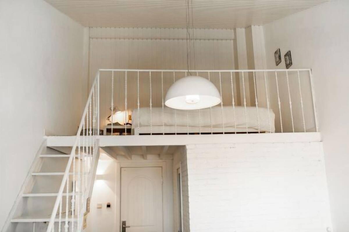 A white interior with a bunk bed, a staircase, and a door.