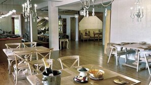 Un comedor amplio con mesas y sillas de madera, un candelabro y vistas a otra habitación.