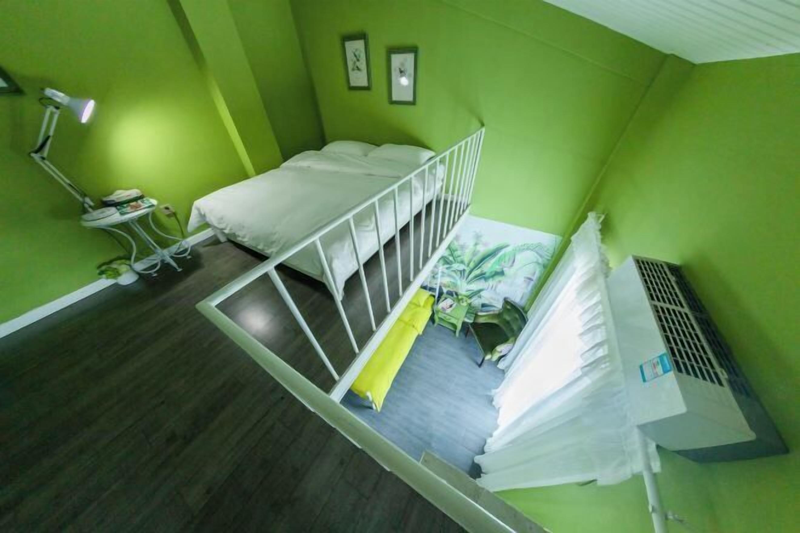 A room with a bunk bed, a desk with a chair, a desk lamp, a radiator, and a plant.