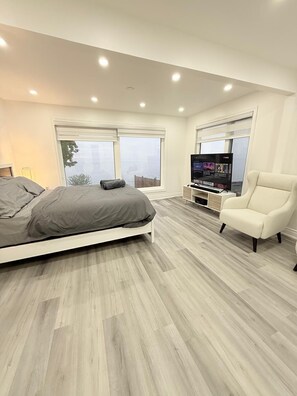 A modern bedroom with a bed, a TV, and a chair. - Lakeview retreat closer to Toronto and Niagara Area (Hamilton)
