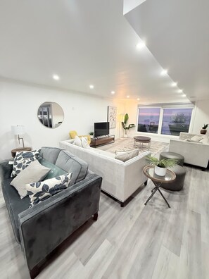 A modern living room with a sofa, a coffee table, and a TV. - Lakeview retreat closer to Toronto and Niagara Area (Hamilton)