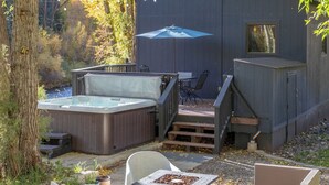 A cabin with outdoor seating, a hot tub, and a deck.