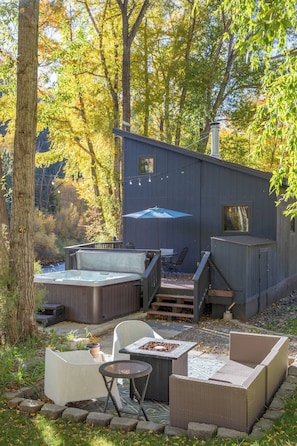A cabin with outdoor seating, a hot tub, and a deck.