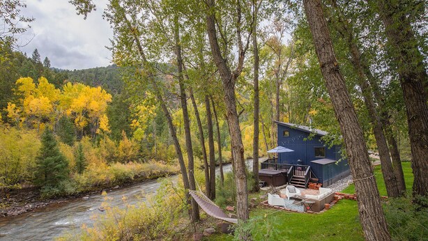 A cabin with a deck, a hammock, and a river view.