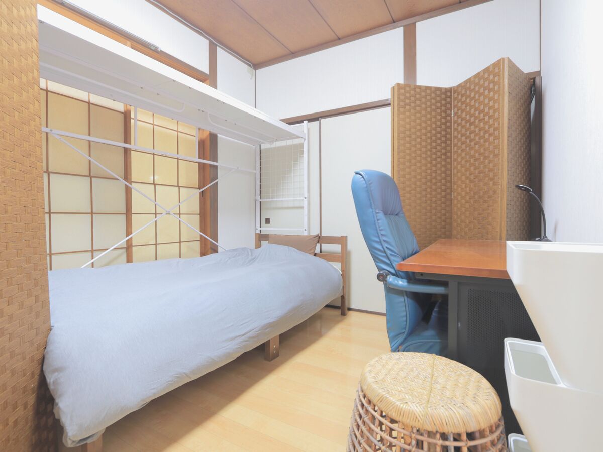 Habitación pequeña con una cama individual, una silla, una mesita y un tabique.