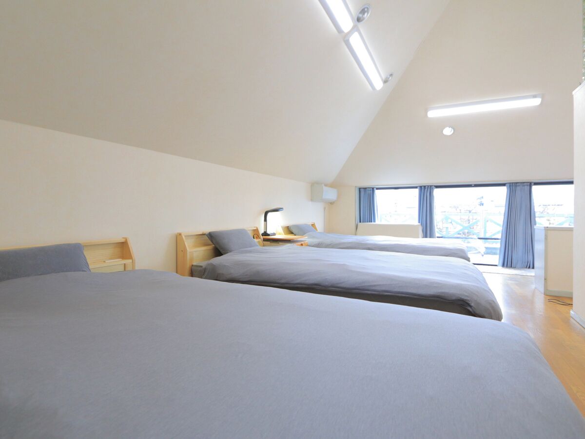 A modern hotel room with two beds, a desk, and a large window with curtains.