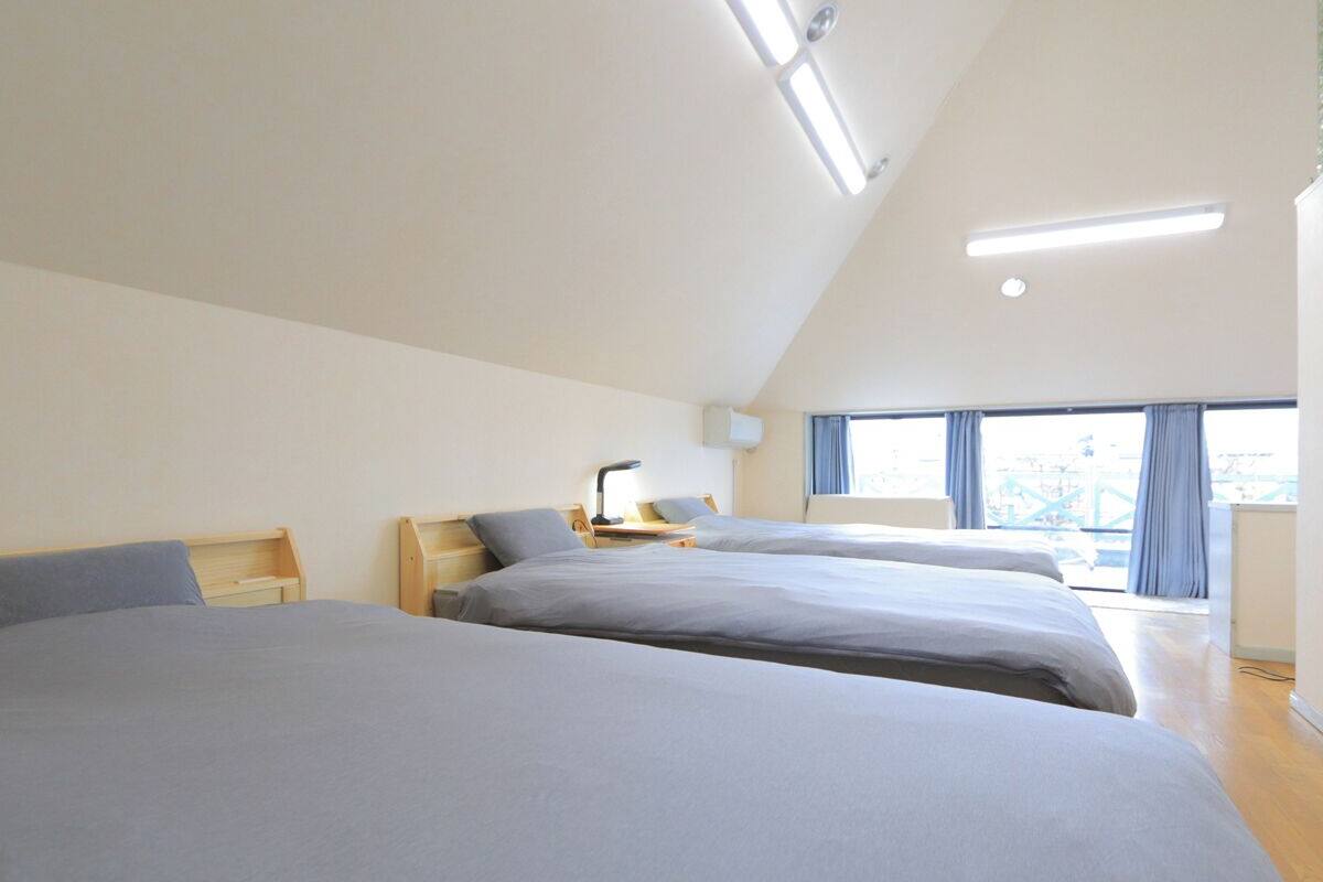 A modern hotel room with two beds, a desk, and a large window with curtains.
