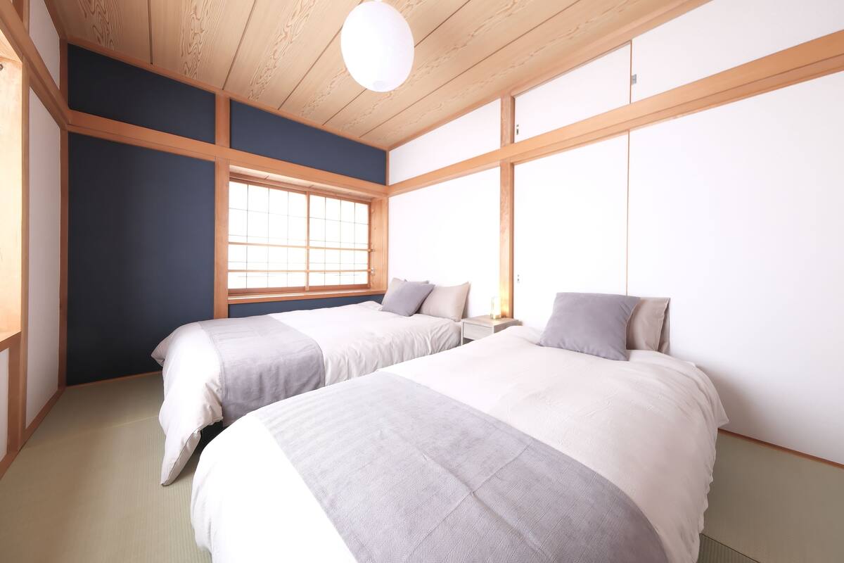 A room with two beds, a window, and a wooden ceiling.