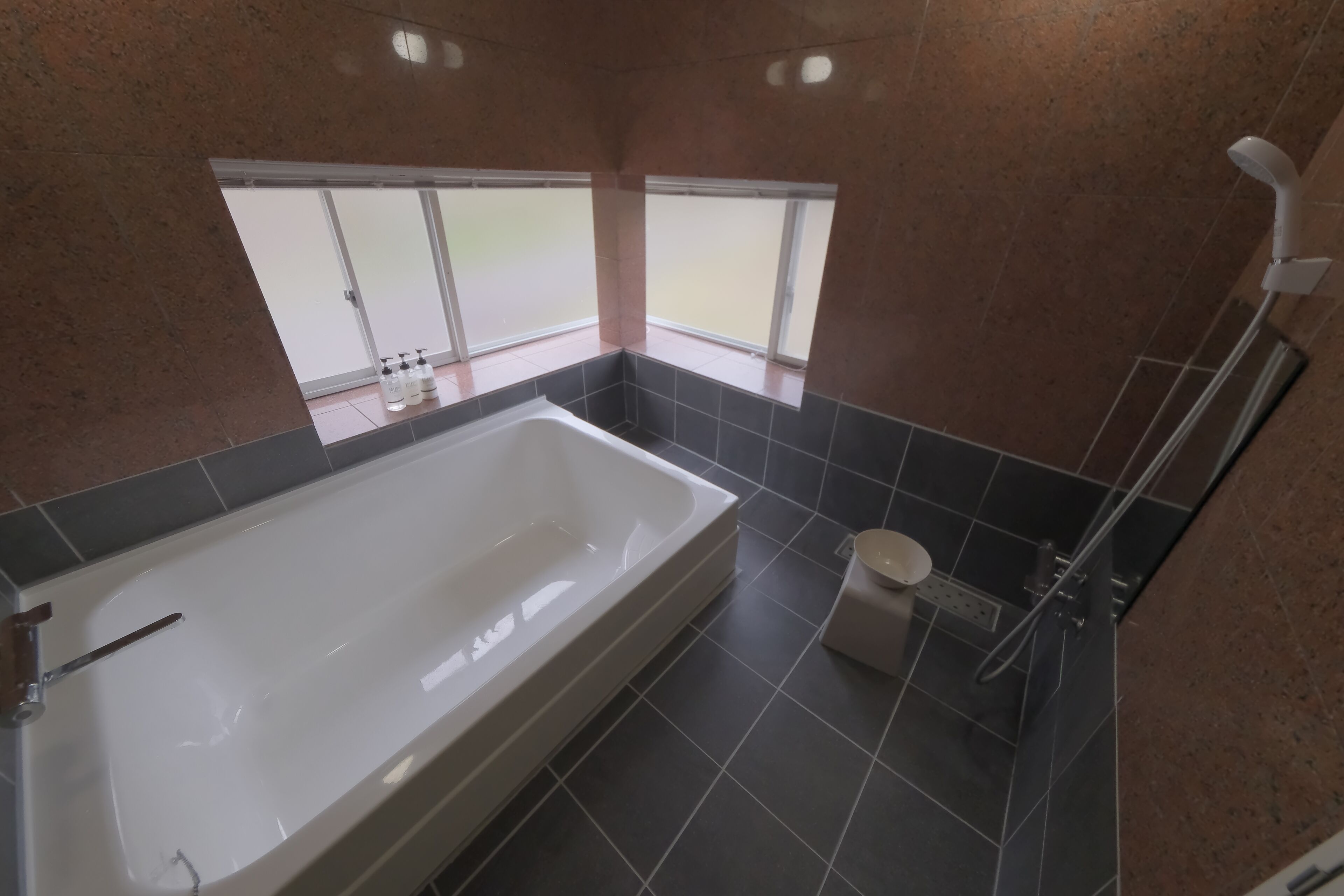 A modern bathroom with a bathtub, toilet, and shower.