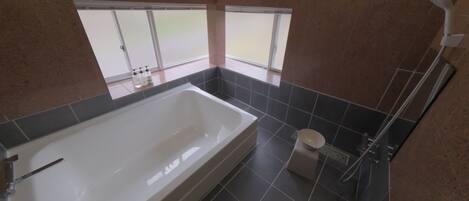 A modern bathroom with a bathtub, toilet, and shower.