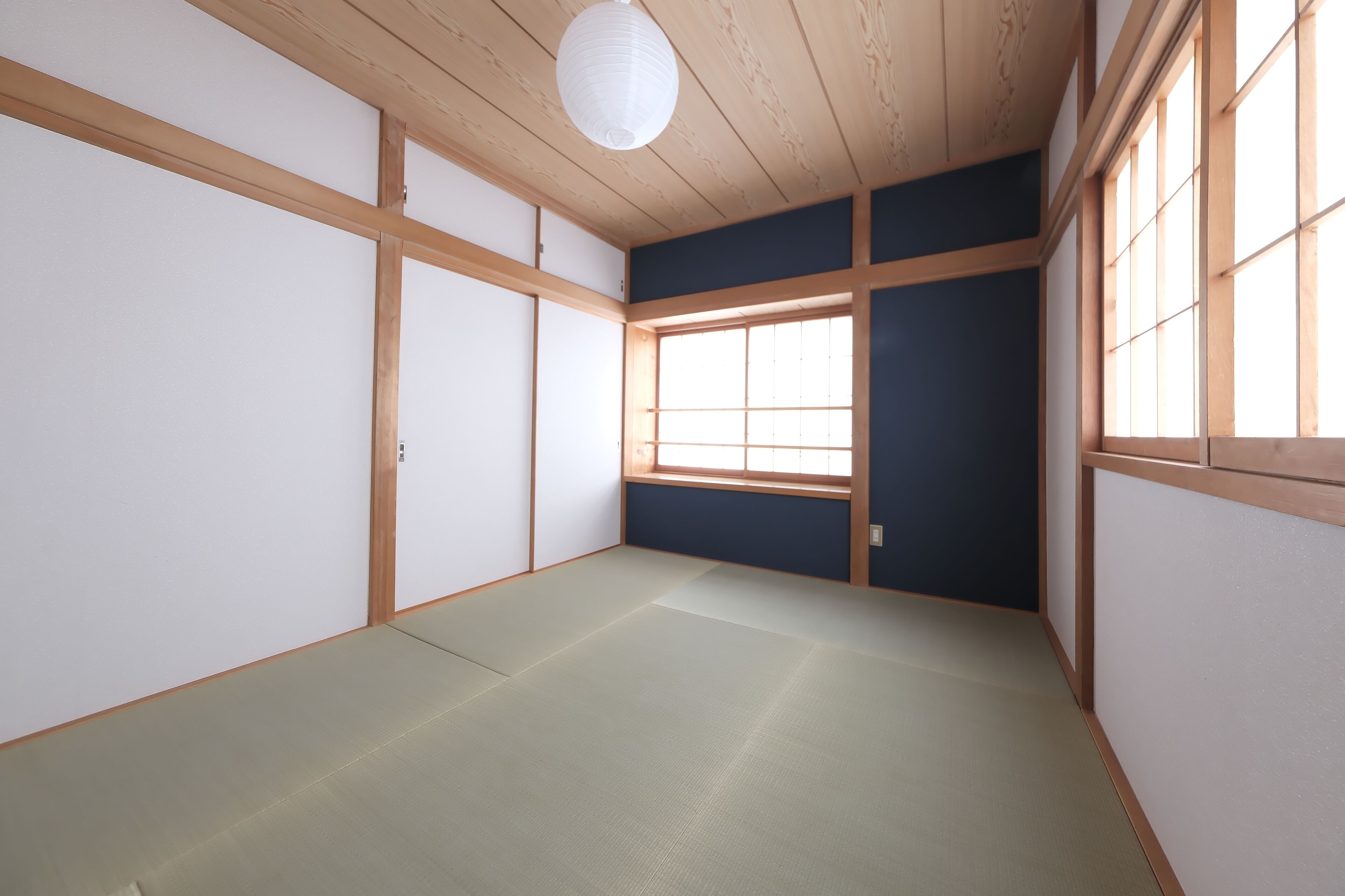 A room with tatami flooring, shoji screens, and a large window.
