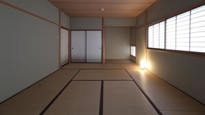 A traditional Japanese room with tatami flooring, sliding doors, and a window with shoji screens. - Shakunagedaira Vacation Rental Lot 1 (Inawashiro)