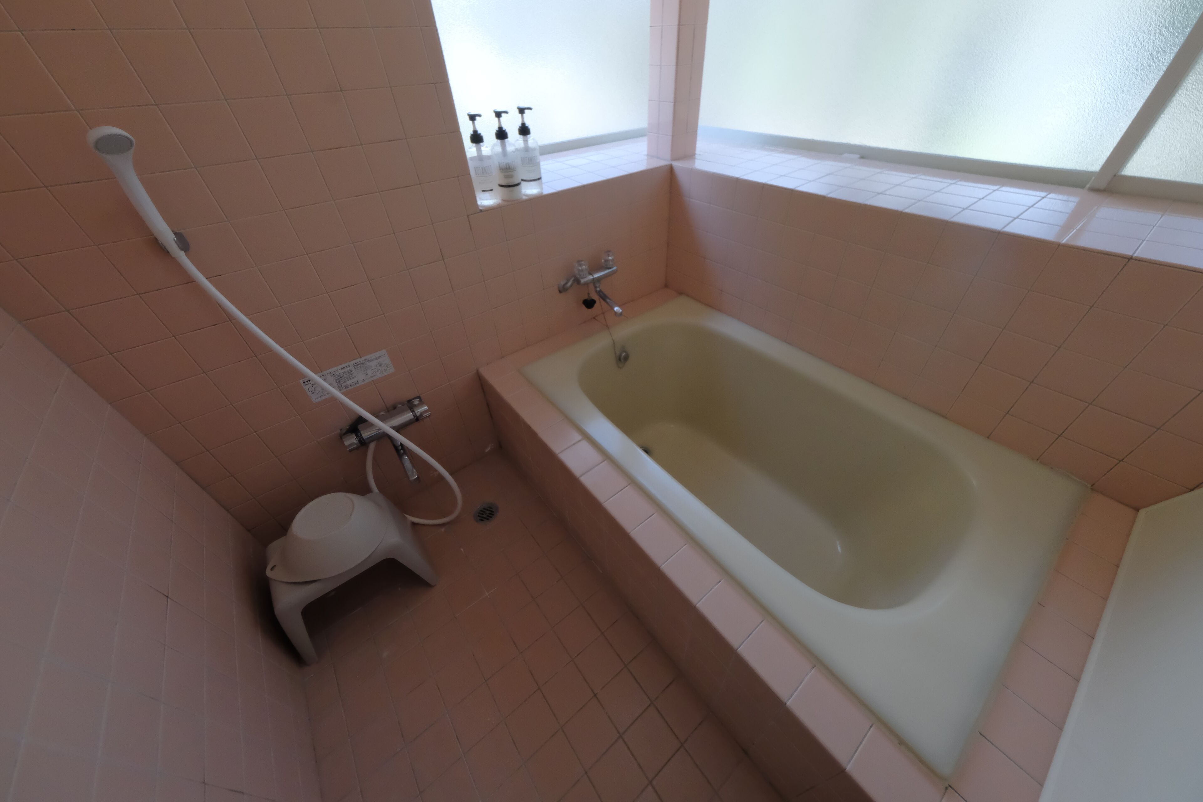 A bathroom with a bathtub, a toilet, and a showerhead.