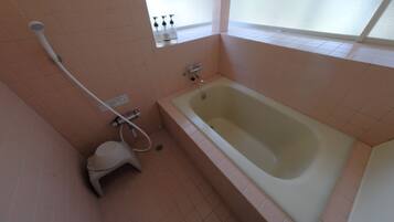 A bathroom with a bathtub, a toilet, and a showerhead.