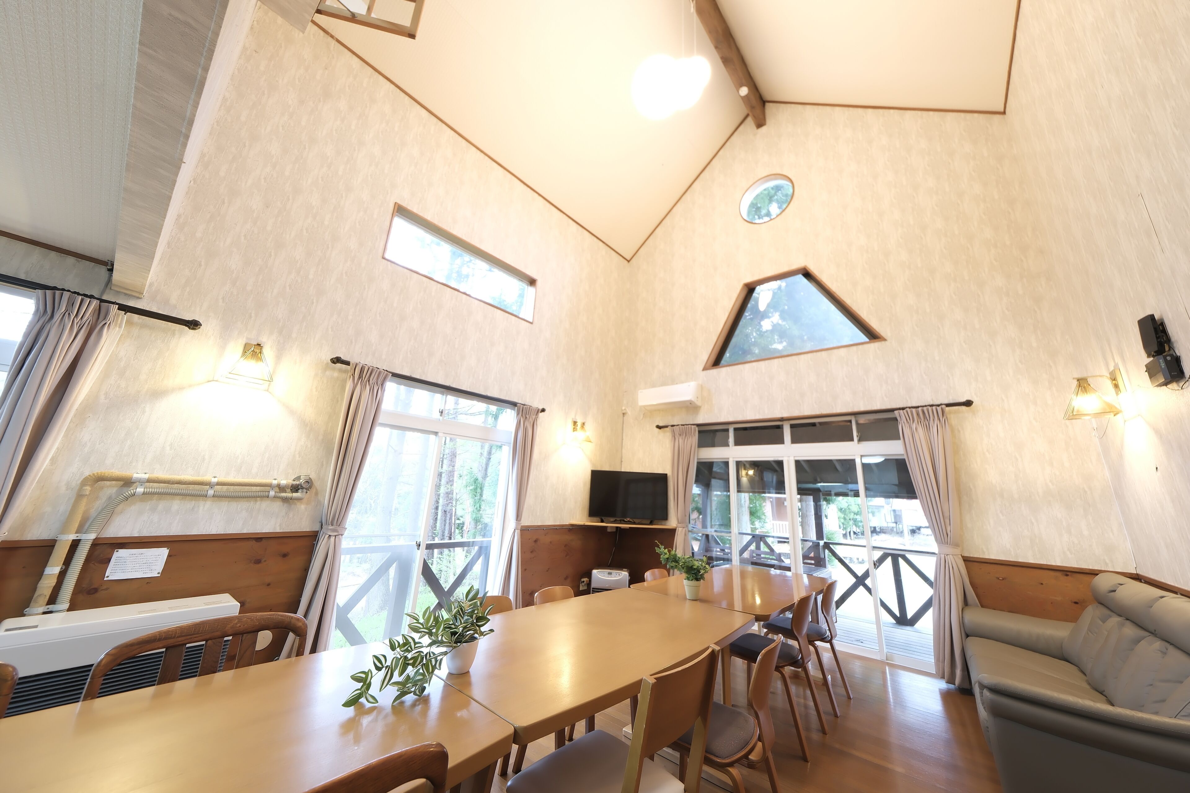 A spacious room with a large table, chairs, a sofa, and a TV.