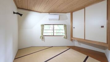 Una habitación con suelo de tatami, una ventana con cortinas, un ventilador de techo y una puerta corredera.