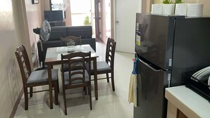 Un espacio habitable compacto con comedor, un refrigerador negro y un sofá.