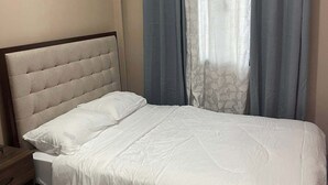 Un dormitorio con cama, cortinas y mesita de noche.