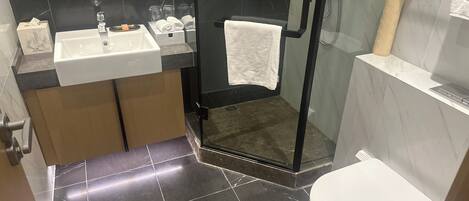 A modern bathroom with a glass-enclosed shower, a white sink, and a toilet.