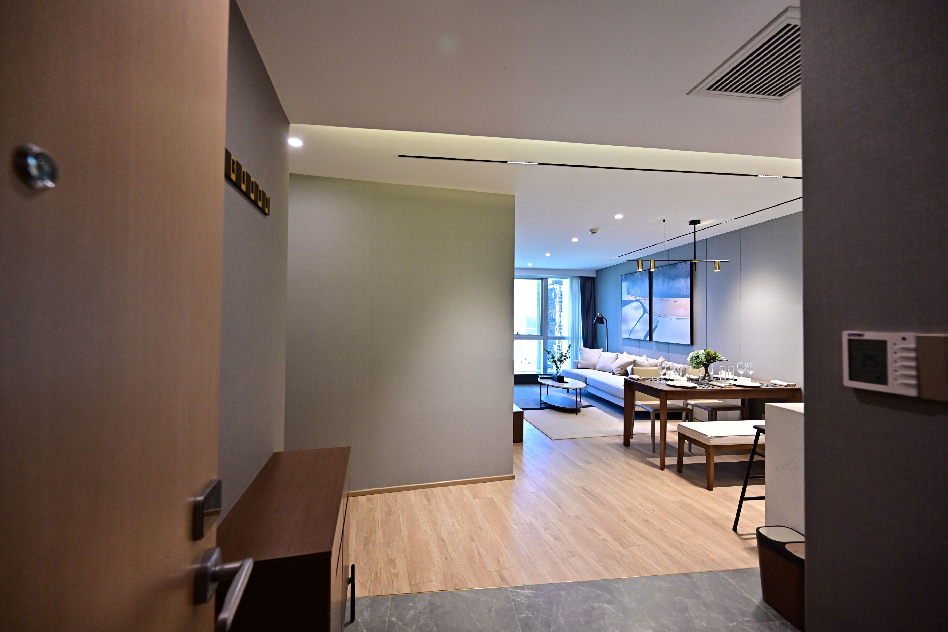 Un interior moderno con un escritorio de madera, una mesa de comedor y un sofá en una habitación luminosa con vistas.