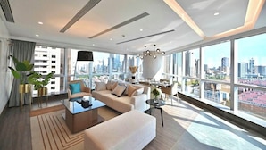 Un salon moderne avec un canapé, une table basse et une vue sur la ville grâce à de grandes fenêtres.