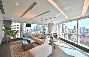 Ein modernes Wohnzimmer mit Sofa, Couchtisch und Blick auf die Stadt durch große Fenster.