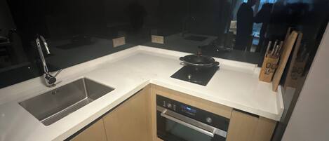 A compact kitchen with a sink, stove, oven, and a knife block.
