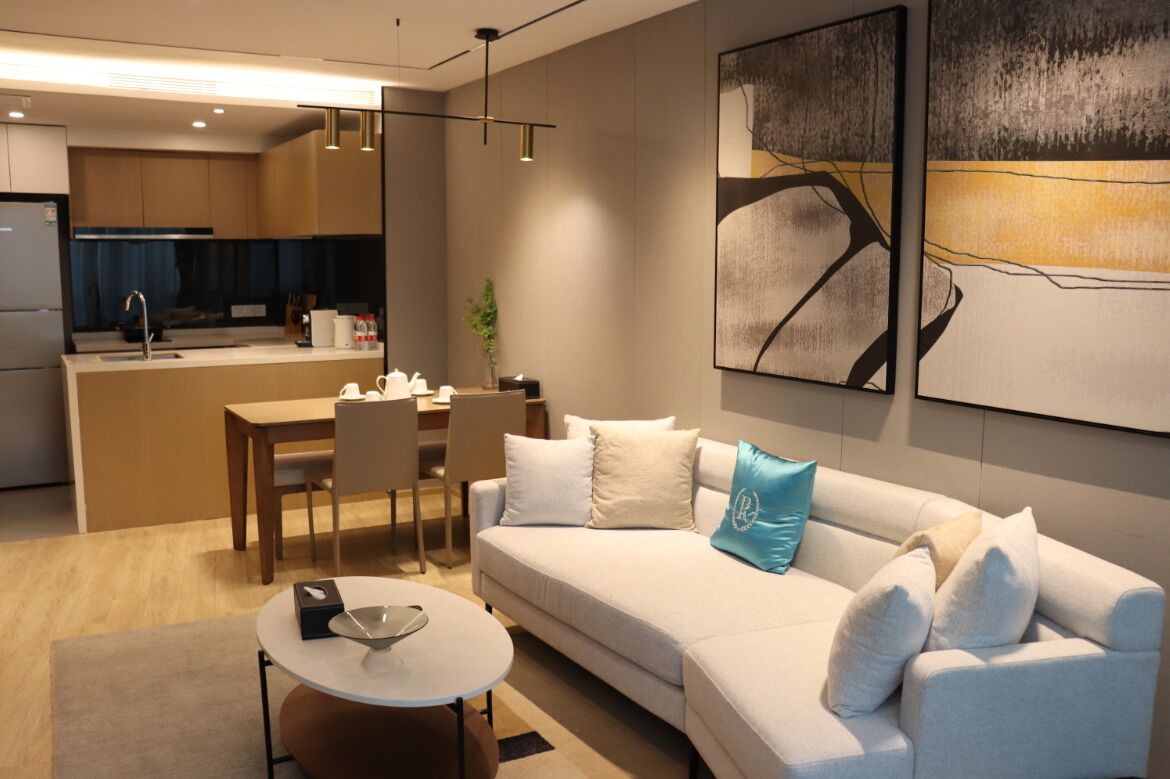 Una sala de estar moderna con un sofá, una mesa de comedor y una cocina al fondo.