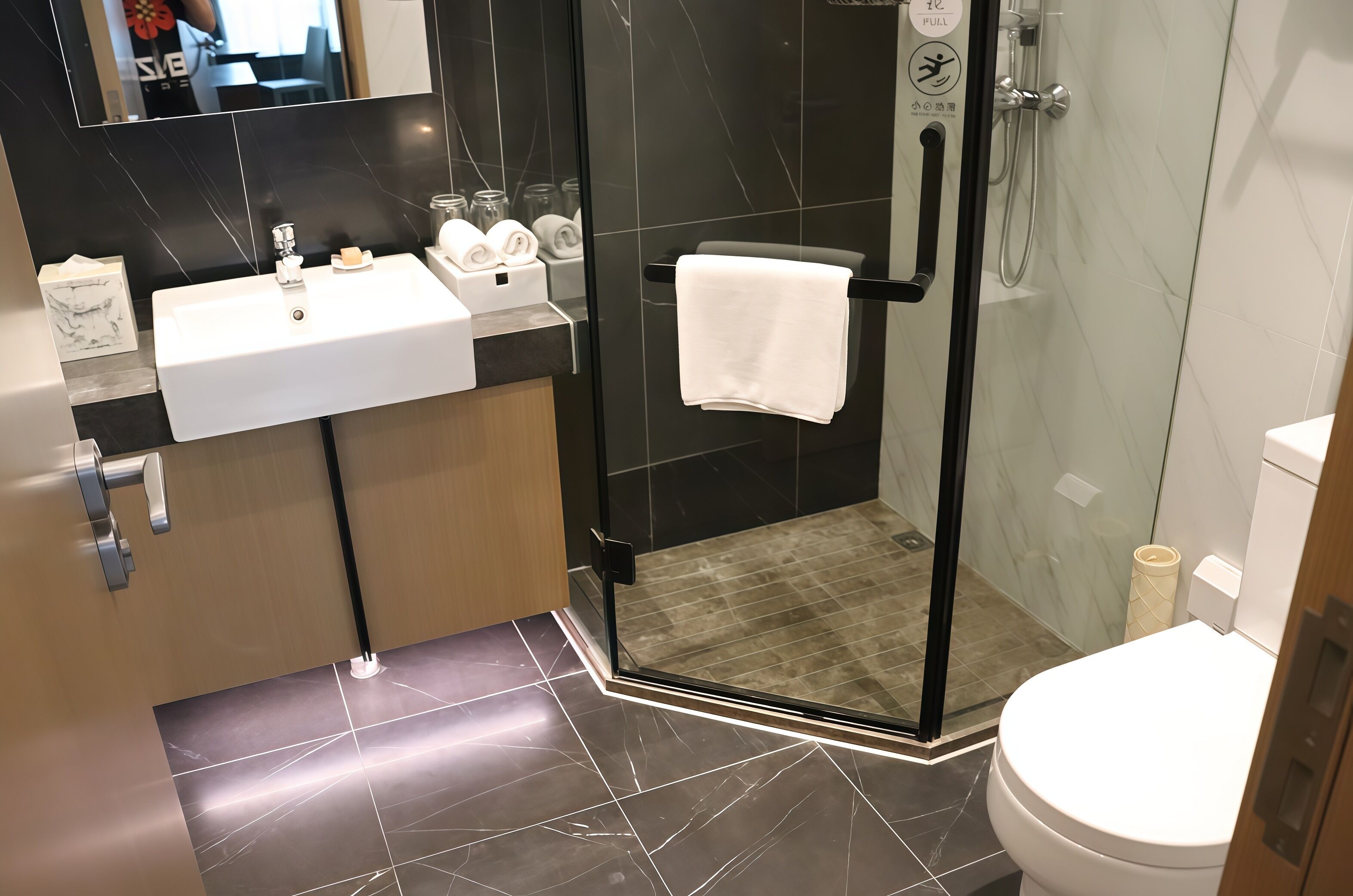 A modern bathroom with a glass-enclosed shower, a white sink, and a toilet.