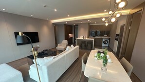 Una sala de estar moderna con un sofá, una mesa de comedor y una zona de cocina con lavadora.