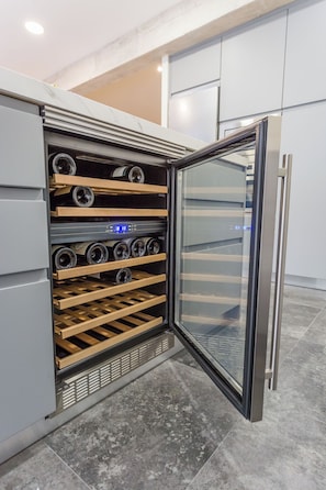 A modern kitchen with a built-in wine cooler, a stainless steel refrigerator, and a glass door cabinet. - Boutique Apartment in Logroño Centro (Logroño)