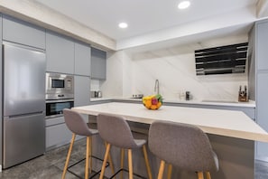 A modern kitchen with a marble backsplash, stainless steel appliances, and a central island with bar stools. - Boutique Apartment in Logroño Centro (Logroño)