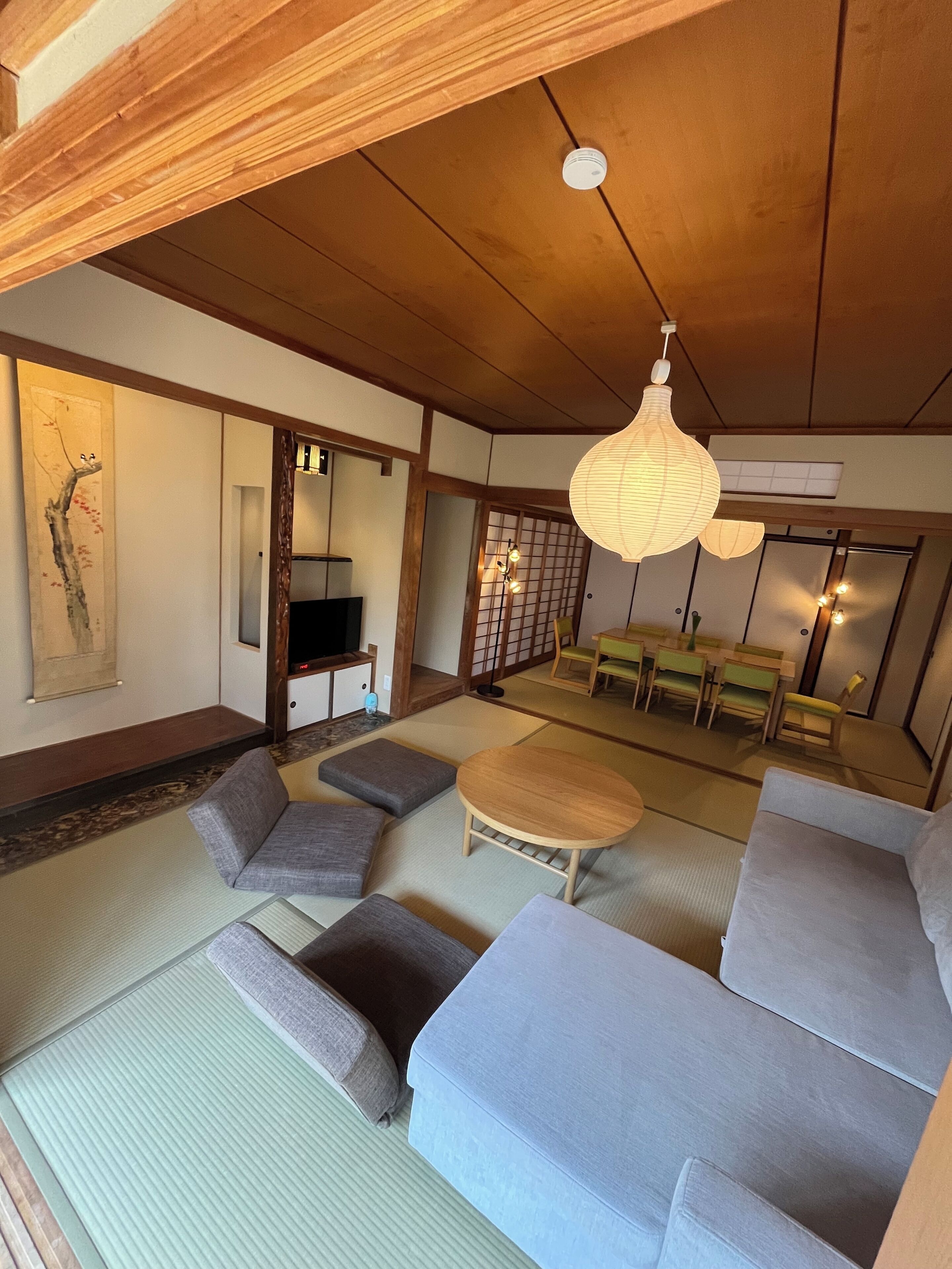 Un soggiorno in stile tradizionale giapponese con pavimento in tatami, arredi in legno bassi e una porta scorrevole.