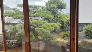 A view through a wooden-framed window of a traditional Japanese garden with a pond, rocks, and various trees. - [Itogi] A Private Rental House in Miyajimaguchi! It's within walking distance of the port where you can take a ferry to the World Heritage Site of Miyajima. Up to 16 people (Hatsukaichishi)