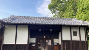 Un edificio japonés tradicional con tejado de tejas, puertas de madera y una pequeña ventana.