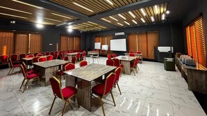 Un salón de conferencias con mesas y sillas, un proyector y una pantalla.