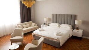 Una habitación de hotel con una cama, dos mesitas de noche, un sofá y una silla.