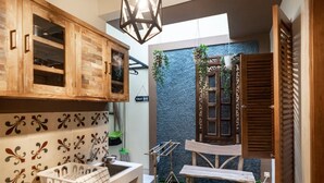 Een kleine keuken met houten kastjes, een spoelbak en een zithoek met een bankje.