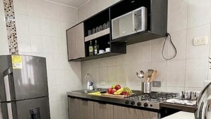 Une cuisine équipée d’un réfrigérateur, d’un four à micro-ondes, d’une cuisinière, d’un évier et de divers ustensiles de cuisine.