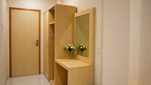 En hall med en trädörr, en spegel och en liten hylla med blommor.
