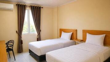 Quarto de hotel com duas camas, uma escrivaninha, uma cadeira e um ar condicionado.