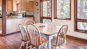 A dining area with a wooden table and chairs, a chandelier, and large windows with a view of trees. - 3 Bedroom Cabin in the Woods located in Yosemite Park (Yosemite National Park)