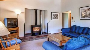 A cozy living room with a fireplace, a blue sofa, a wooden coffee table, and a television on a wooden stand. - 3 Bedroom Cabin in the Woods located in Yosemite Park (Yosemite National Park)