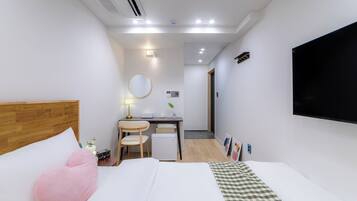 Une chambre d’hôtel équipée d’un lit, d’un bureau, d’une chaise, d’une télévision et d’un petit réfrigérateur.